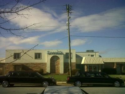 Two black limousines parked in front of a building with 