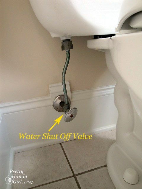 Close-up of a toilet with a water shut-off valve on the wall labeled with an arrow.