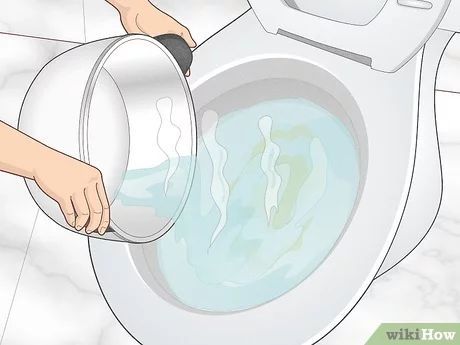 Person pouring water from a pot into a toilet.