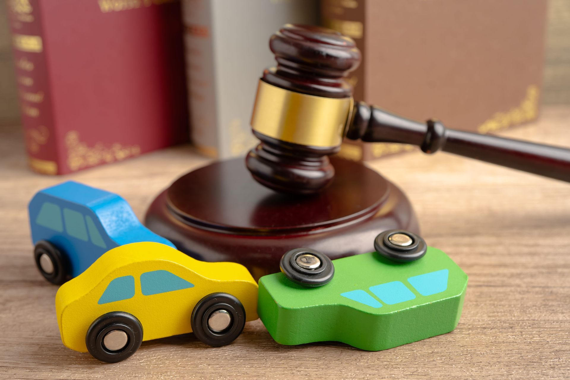 Toy cars beside a judge’s gavel on a desk, suggesting a legal case involving vehicles