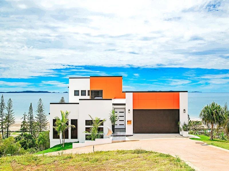 Modern house with white walls and bright orange accents overlooking the ocean