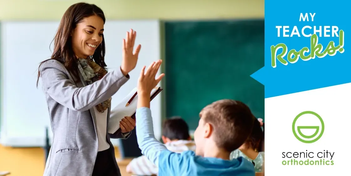 A teacher is giving a high five to a student in a classroom.