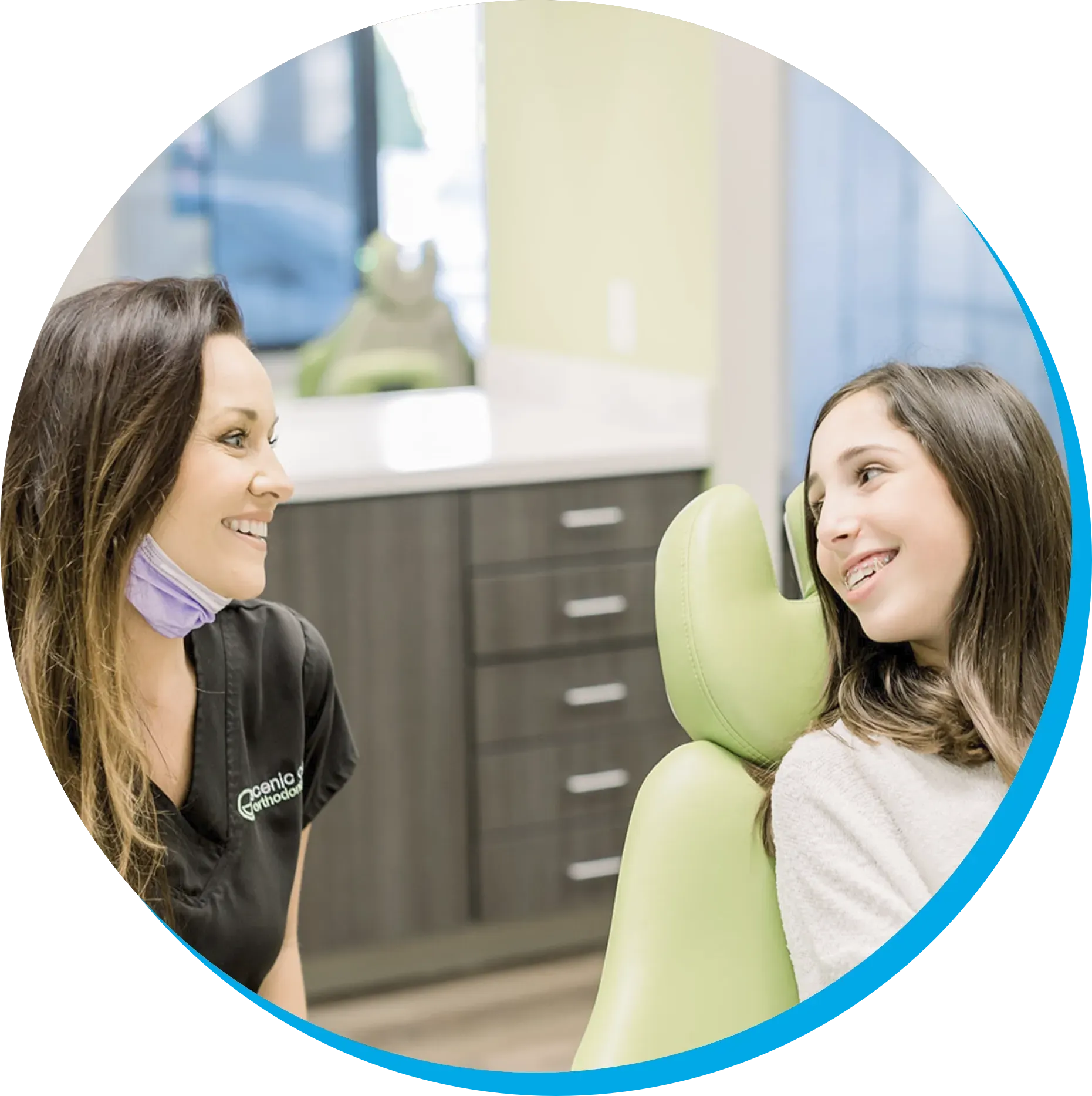 A woman is talking to a young girl in an orthodontic chair.