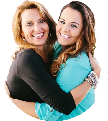 Two women hugging, one has clear braces on her teeth