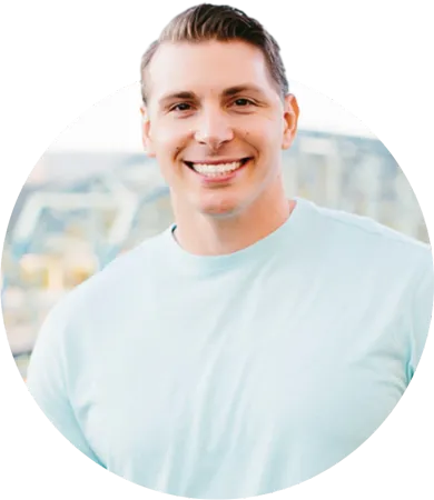 A man in a light blue shirt is smiling for the camera.