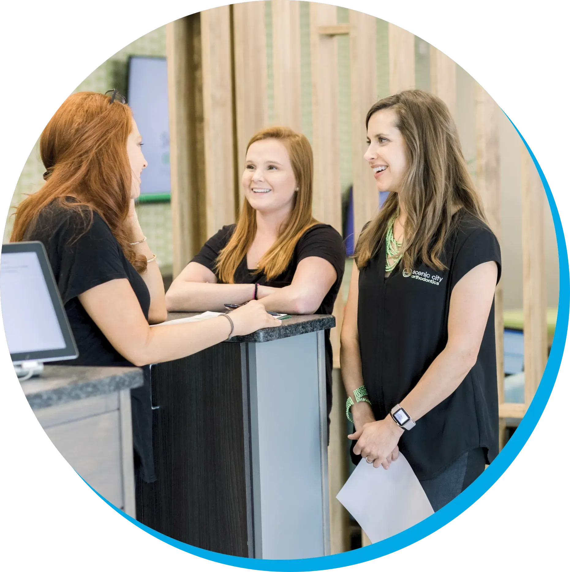 Three women are standing at a counter talking to each other.