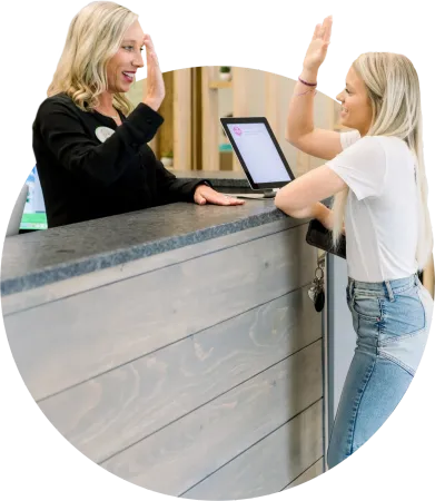 Two women are giving each other a high five at a counter.