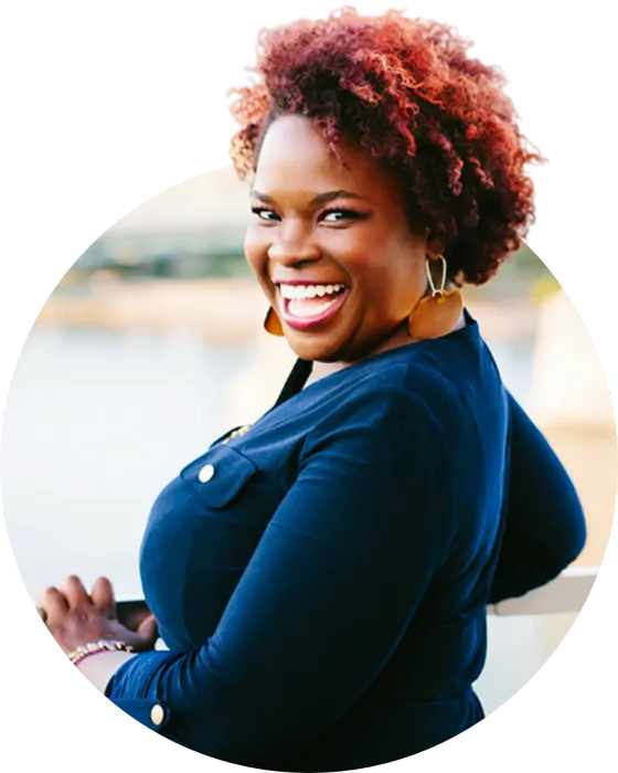 A woman with red hair is smiling and wearing a blue shirt