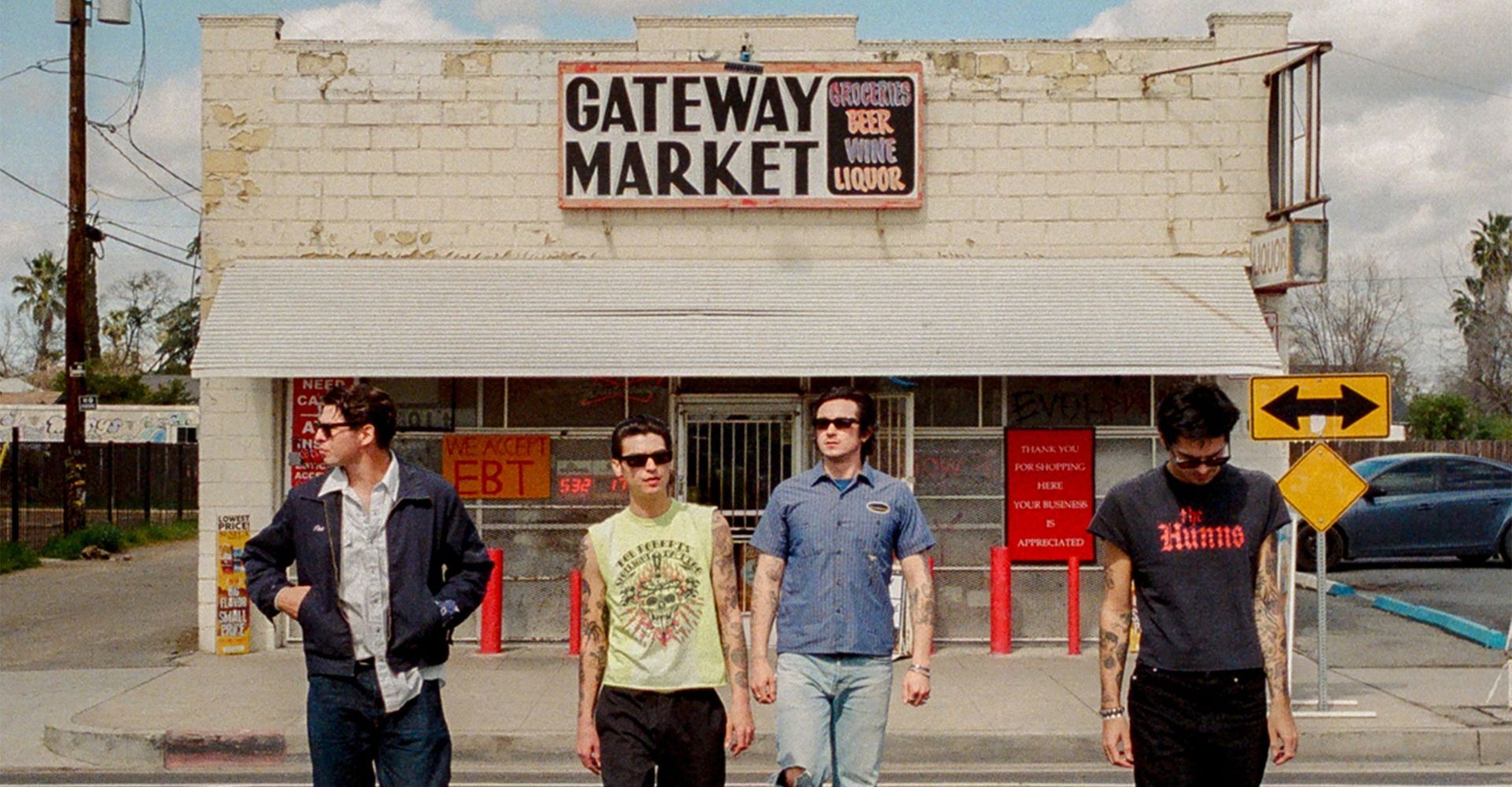 Four men standing outside Gateway Market storefront on a sunny day