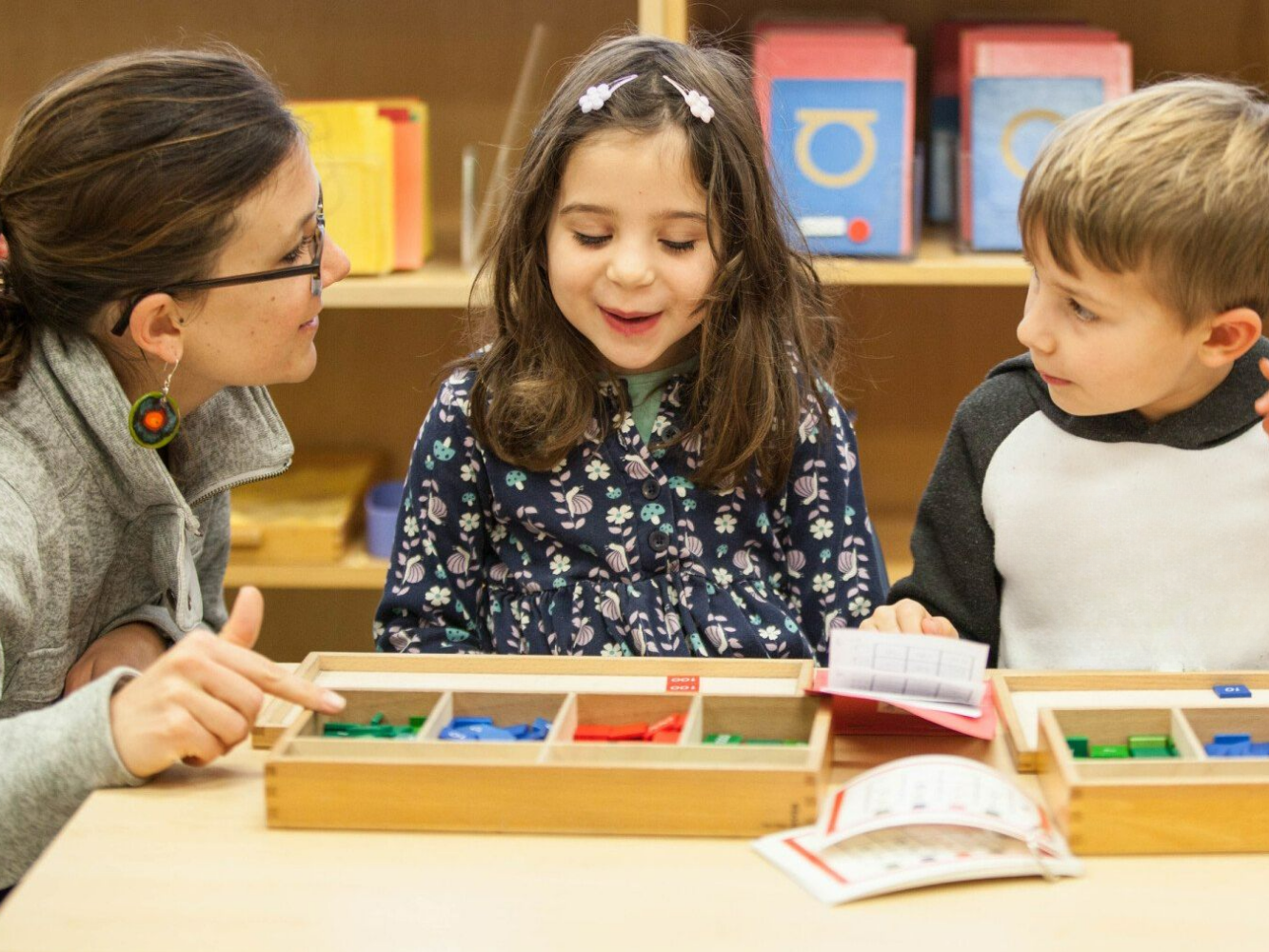 montessori children working with a wooden learning toy at a classroom table