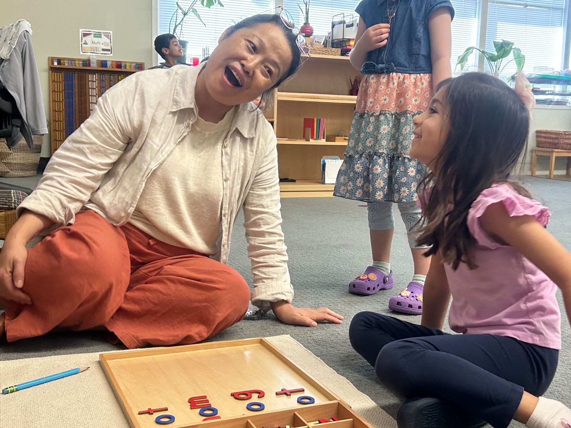 Montessori guide and child working in the classroom