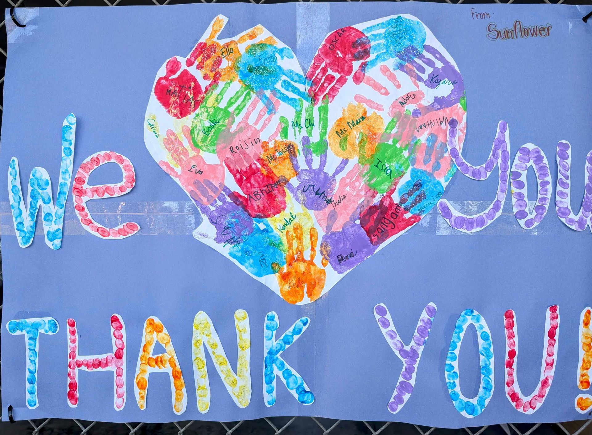 Poster: colorful handprints in a heart shape, saying 
