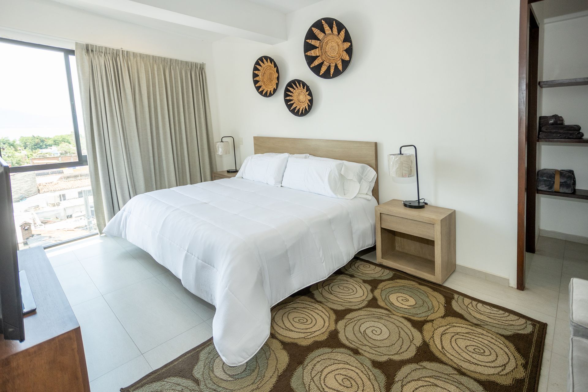 Habitación luminosa con cama confortable, decoración acogedora y acceso a balcón privado con vistas a la ciudad.