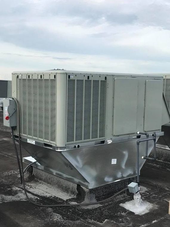Large rooftop HVAC unit on a flat industrial roof under a cloudy sky