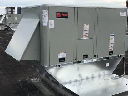 Gray rooftop HVAC unit with open side panel and ductwork on a flat roof