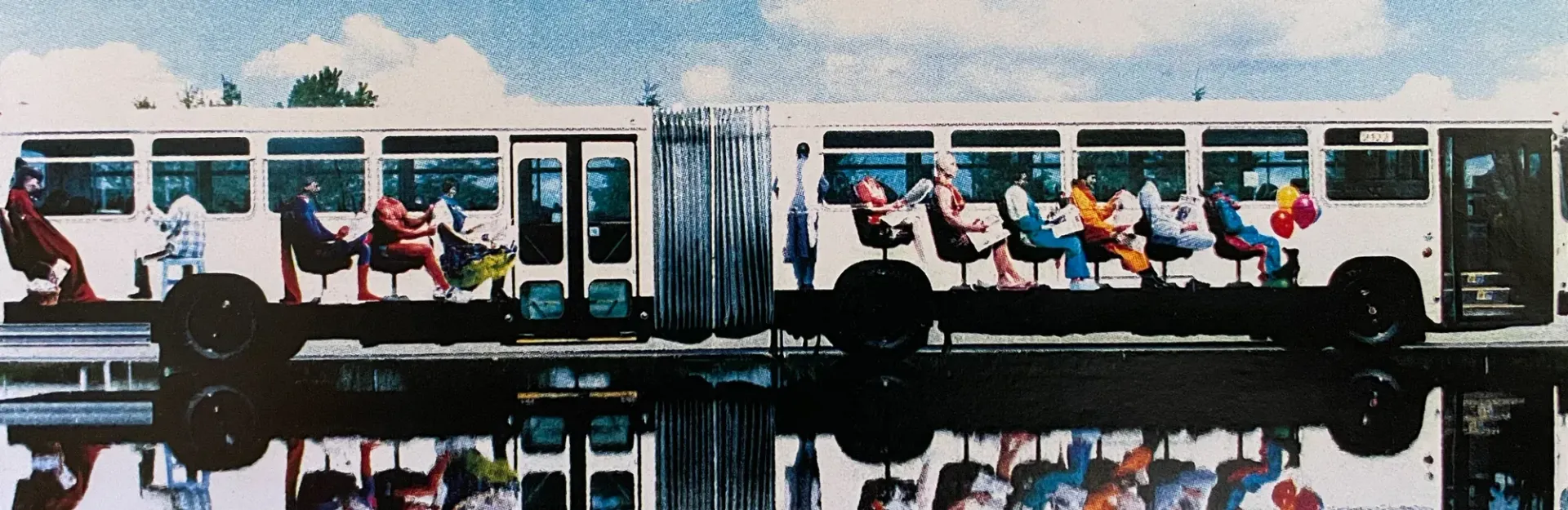 A bus full of seated passengers reflected in water, with a cloudy sky above.