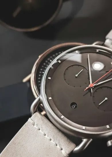 Close-up of a silver analog wristwatch with a dark face and brown leather strap