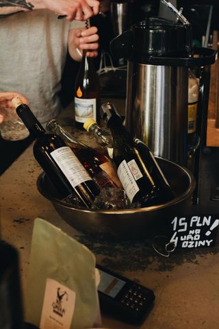 Wine bottles in a bucket of ice beside a coffee urn on a bar counter