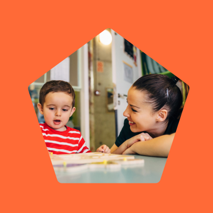 A woman and a child are sitting at a table looking at something.