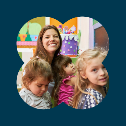 A woman is holding three little girls in her arms.