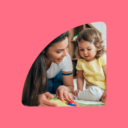 A woman and a little girl are sitting on the floor playing with toys.