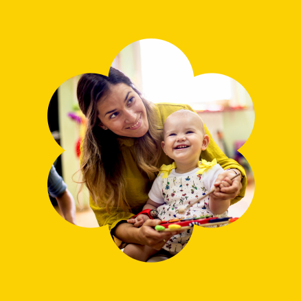 A woman is holding a baby in her arms on a yellow background.