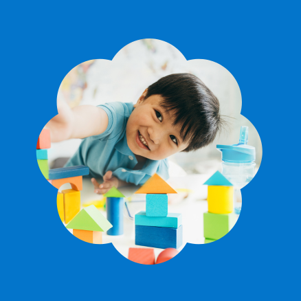 A little boy is playing with wooden blocks on a blue background