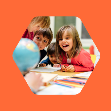 A group of children are sitting around a table looking at a globe.