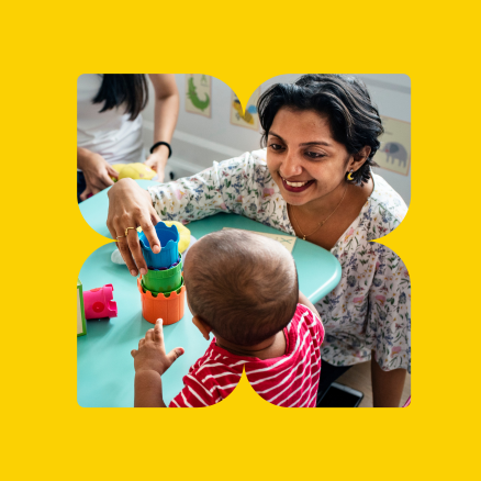 A woman is playing with a baby at a table.