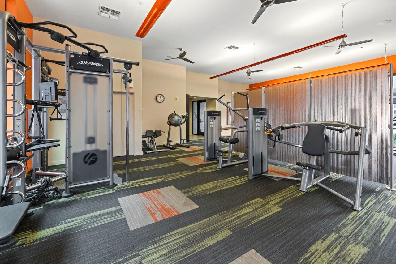 Indoor community gym with weight machines, cable stations, and free weights.