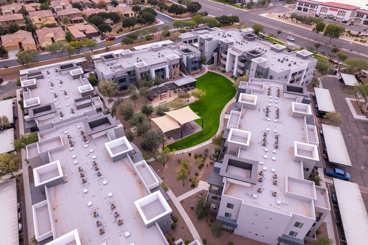 Aerial view of a modern apartment community with a central green courtyard and shaded pavilion at Vive Apartments in Chandler, AZ.