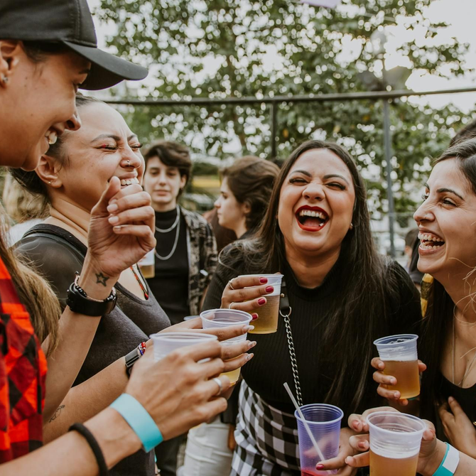 Group of people laughing, holding drinks outdoors  at Vive Apartments in Chandler, AZ.