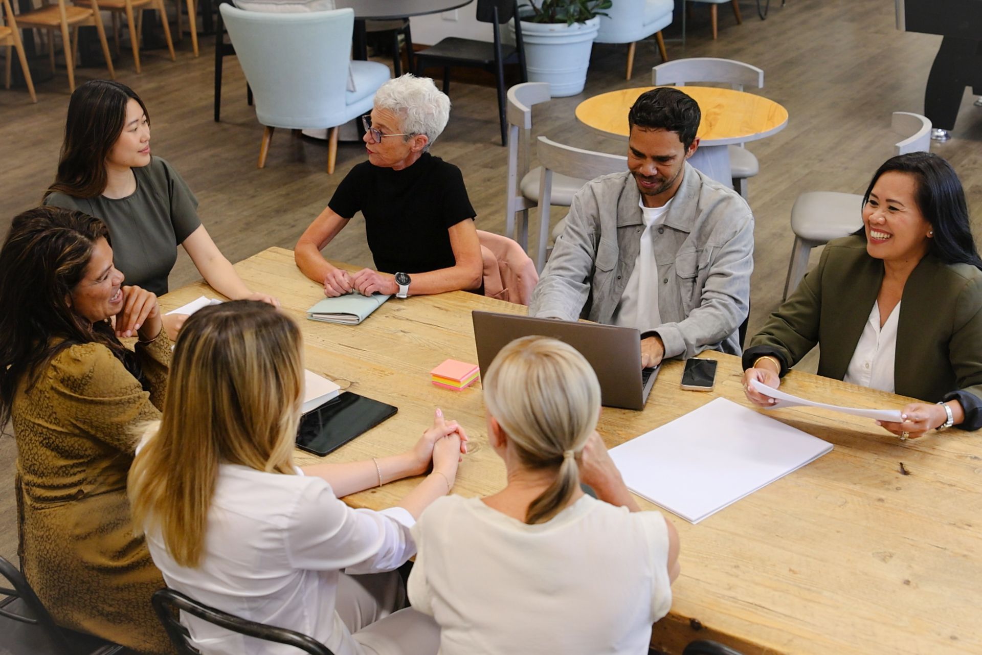 People in a meeting around a table, discussing papers in a bright office lounge