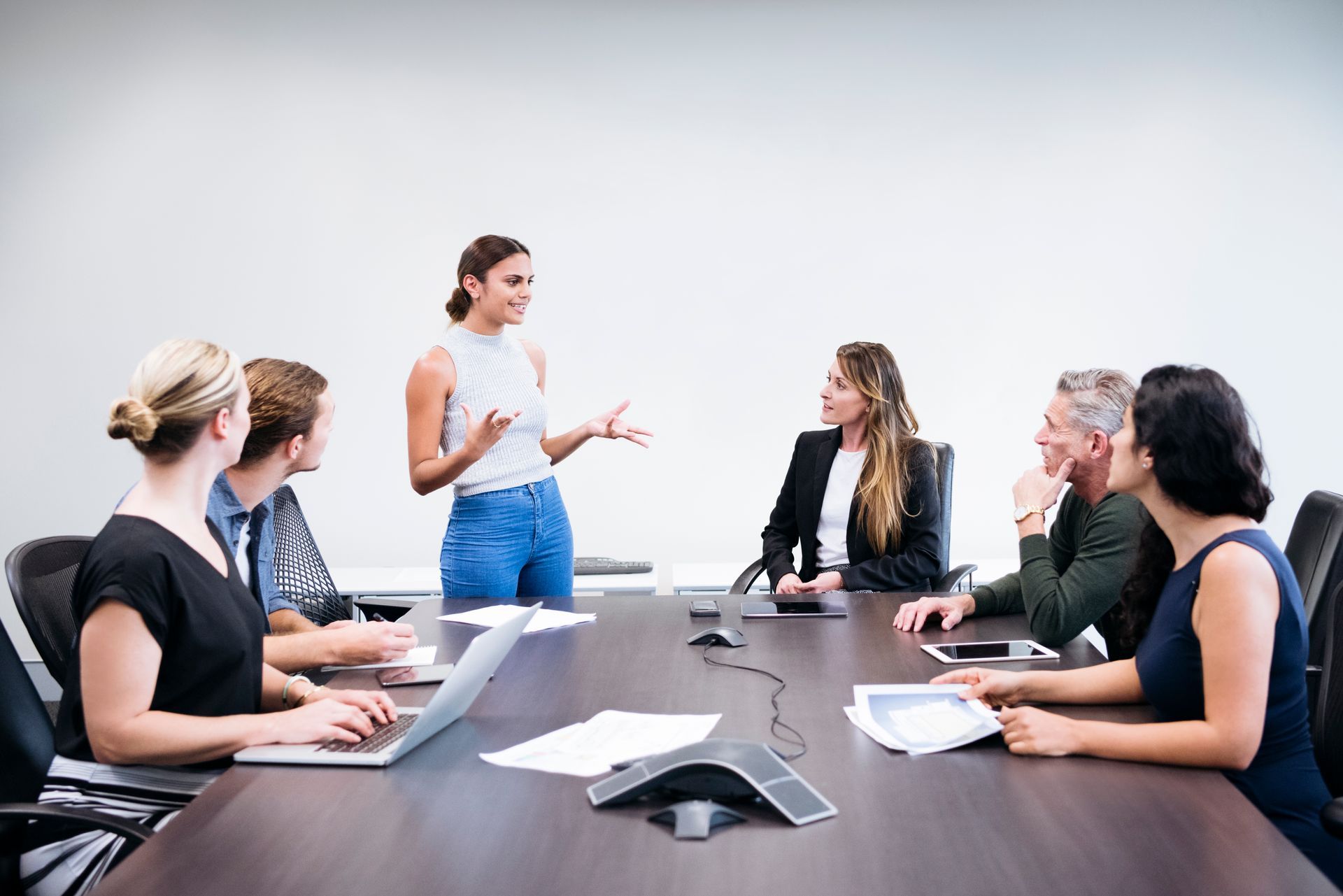 Instructor leading a discussion with seated students in a classroom near a TV screen