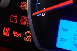 Car dashboard with warning lights glowing red and an illuminated blue trip odometer display