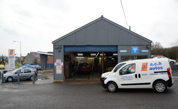 Gray auto repair garage with a white A-to-B Autos van parked outside on a wet day