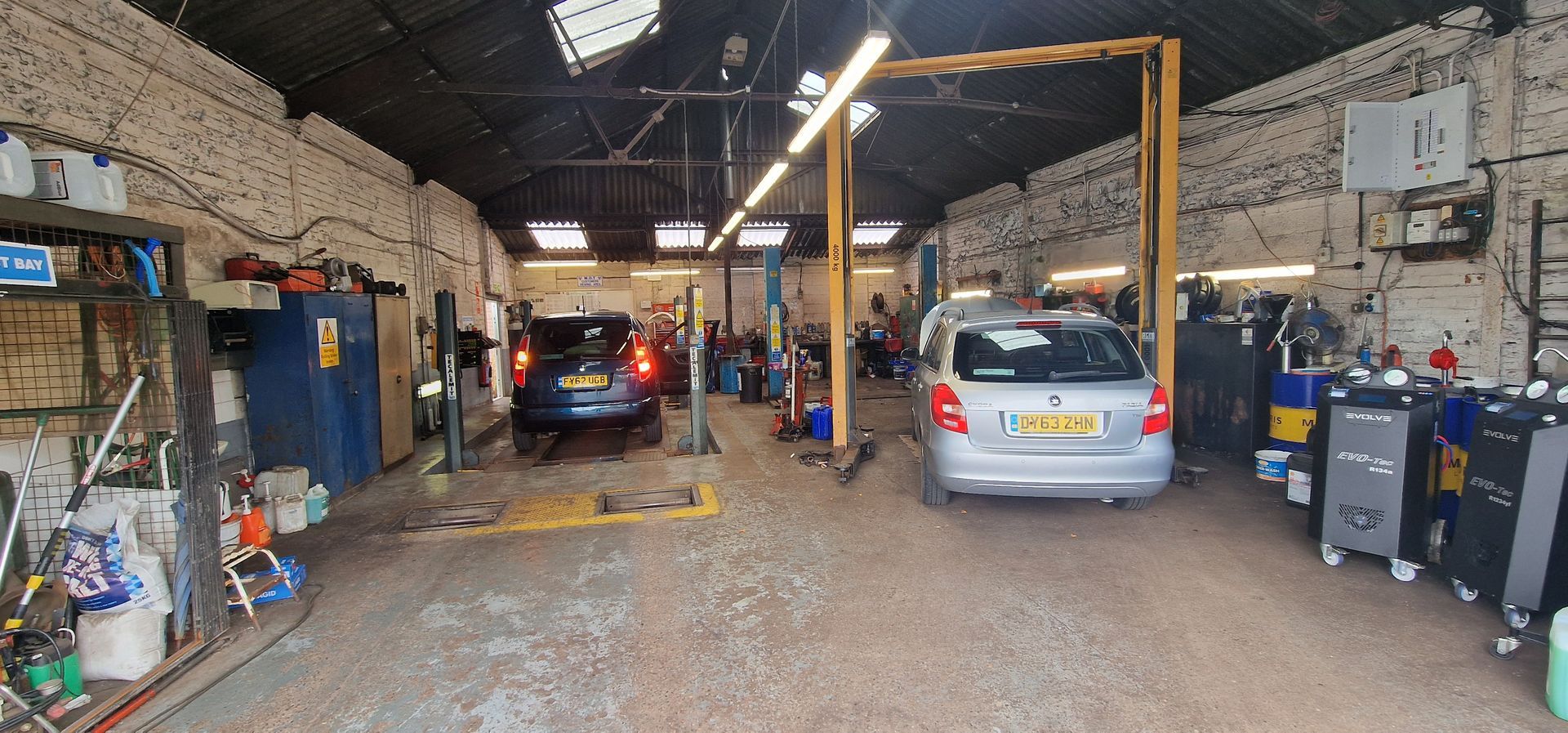 Interior of a car repair garage with two cars and tools along the walls