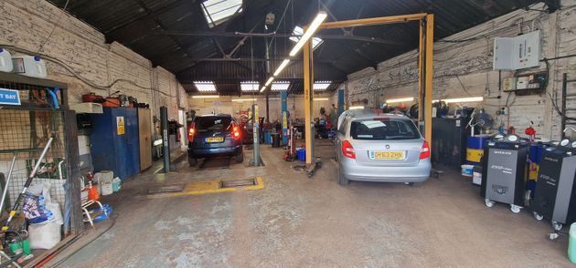 Interior of a car repair garage with two cars and tools along the walls