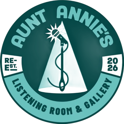 Round teal logo: "Aunt Annie's Listening Room & Gallery." A microphone and needle within a spotlight. "Re-Est. 2026."