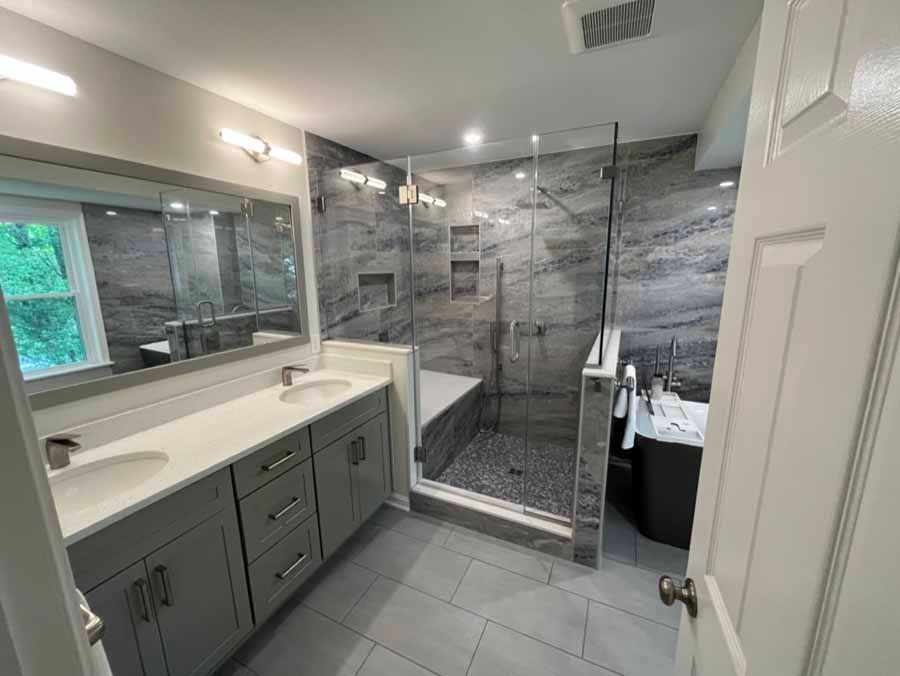 Modern bathroom with gray tile shower, glass door, vanity, and large mirror
