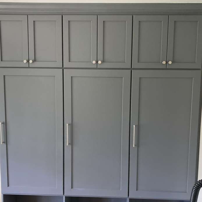 Gray built-in cabinet wall with upper and lower paneled doors and silver handles