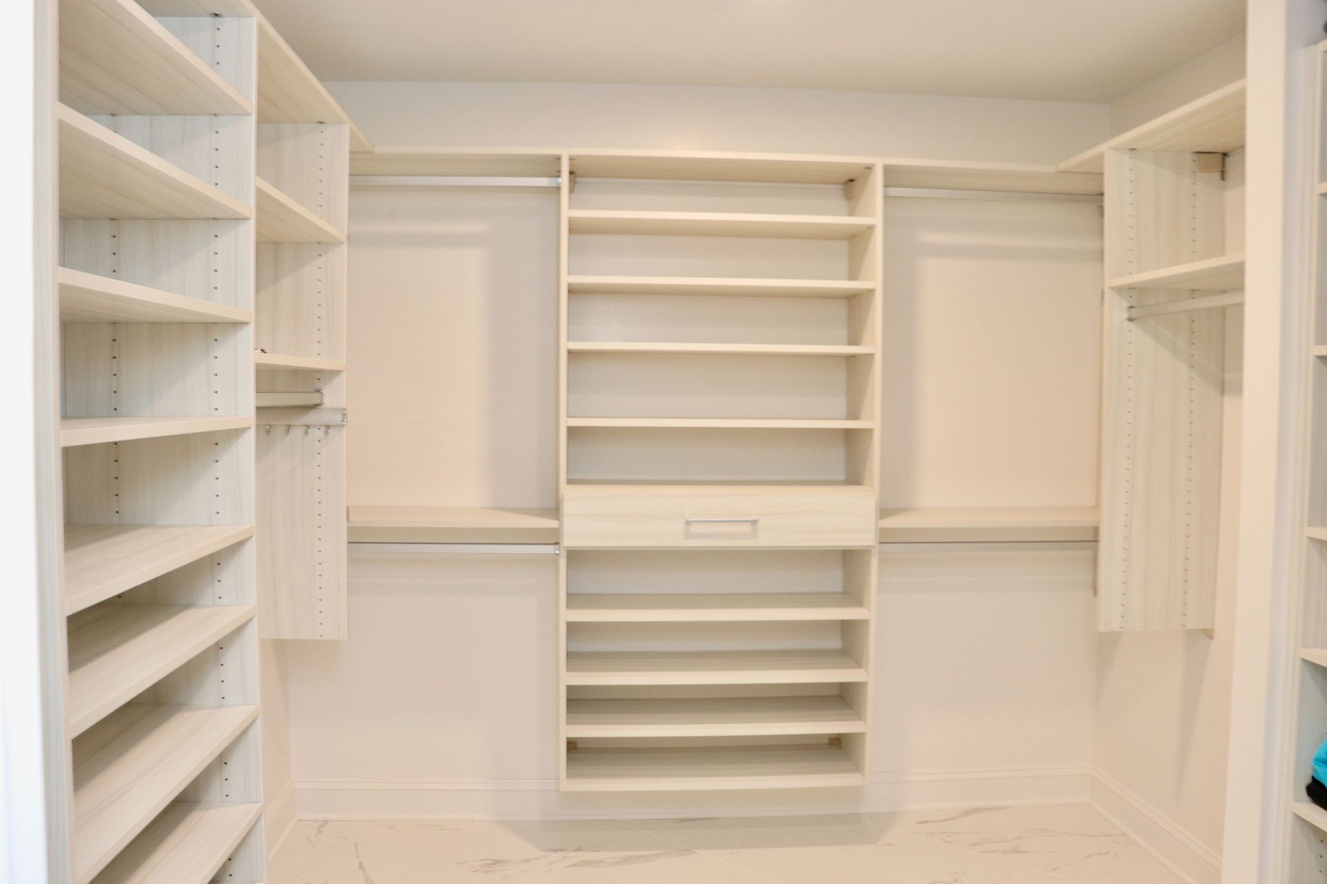 Empty white walk-in closet with built-in shelves and hanging rods