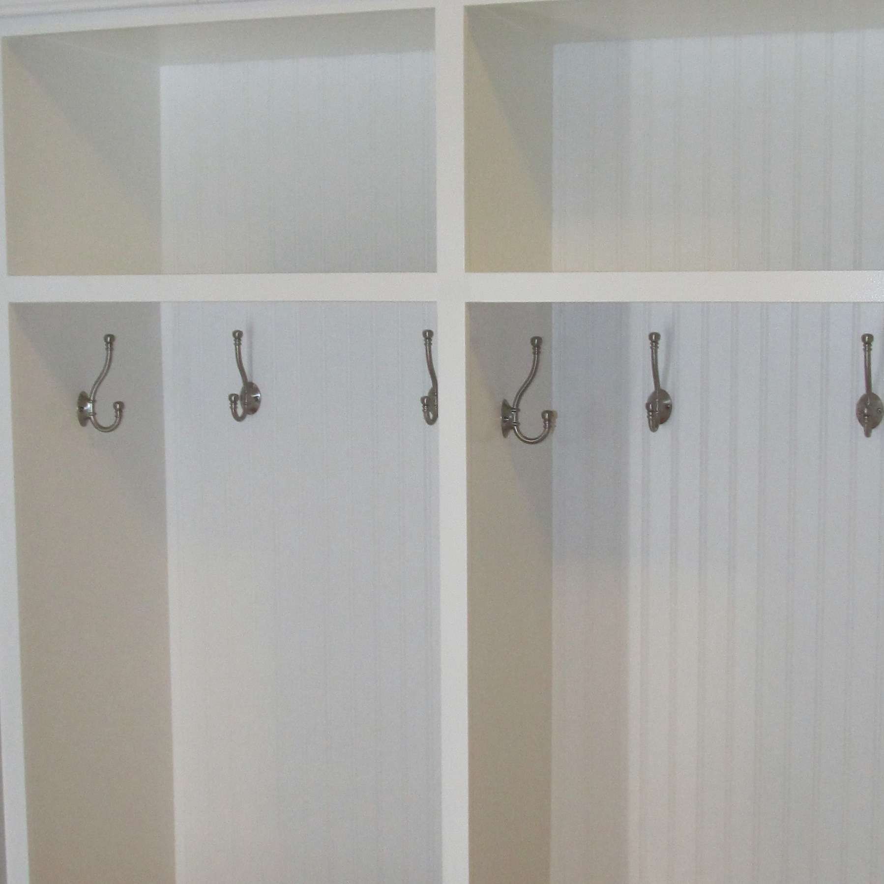 White closet with shelves and hanging hooks inside.