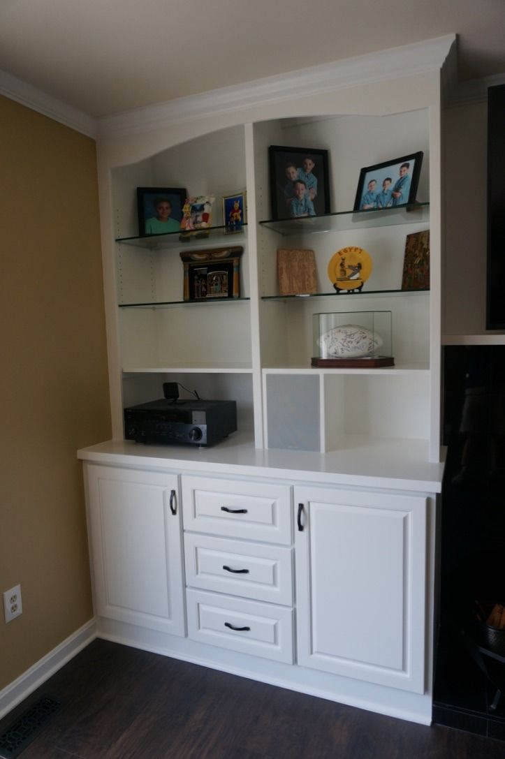 Built-in white shelving and cabinet unit with books, decor, and framed photos in a living room.