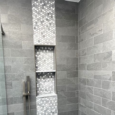 Modern gray tiled shower with a built-in hex tile shelf niche