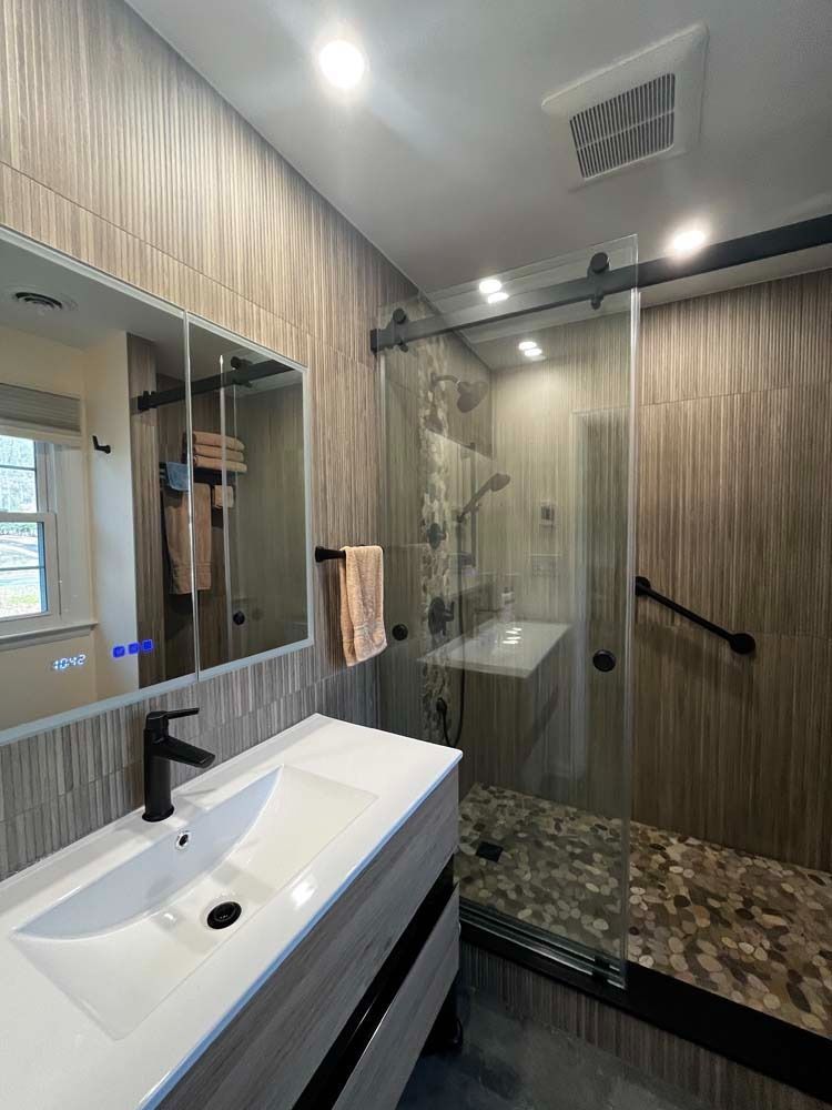 Modern bathroom with glass shower, white sink vanity, and marble countertop
