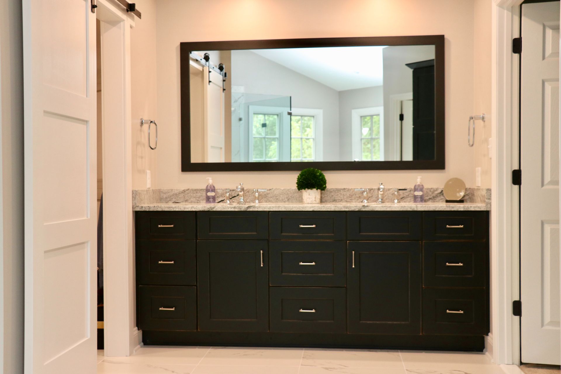 Bathroom vanity with dark cabinets, large mirror, and light walls and tile floor.