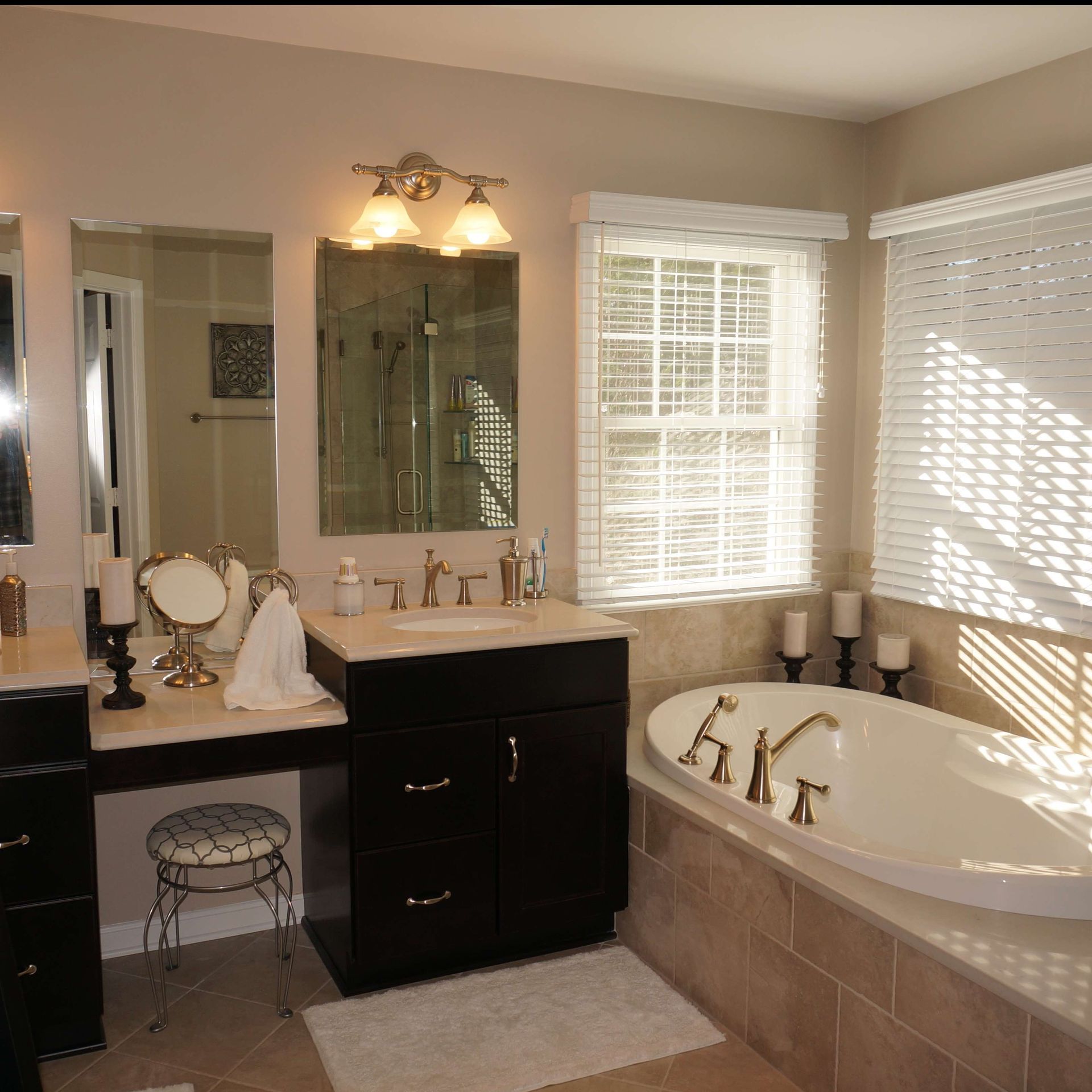 Modern bathroom with double vanity, large mirror, and white soaking tub by bright windows