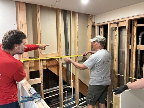 People measuring wall framing during a home renovation project