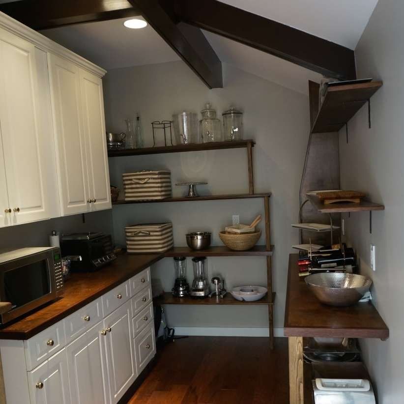 Compact kitchen with white cabinets, wood countertops, open shelves, and exposed beams.